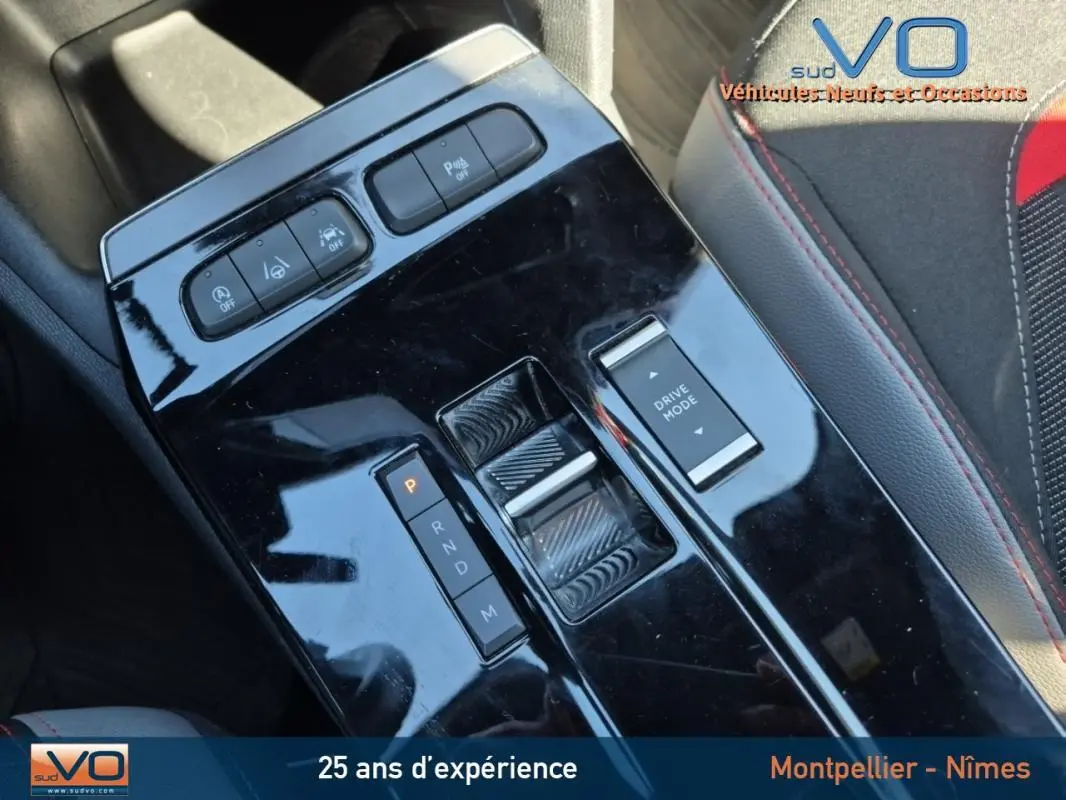 Gros plan sur la console centrale noire brillante de l'Opel Mokka gris clair, avec commandes de boîte auto et mode de conduite.