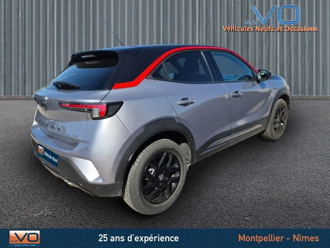 Opel Mokka gris clair vue 3/4 arrière droit avec toit noir et liseré rouge, jantes alliage noires 18 pouces.