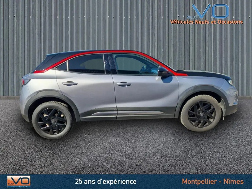 Profil droit d'un Opel Mokka gris clair 2022 avec toit rouge et jantes alliage noires de 18 pouces.