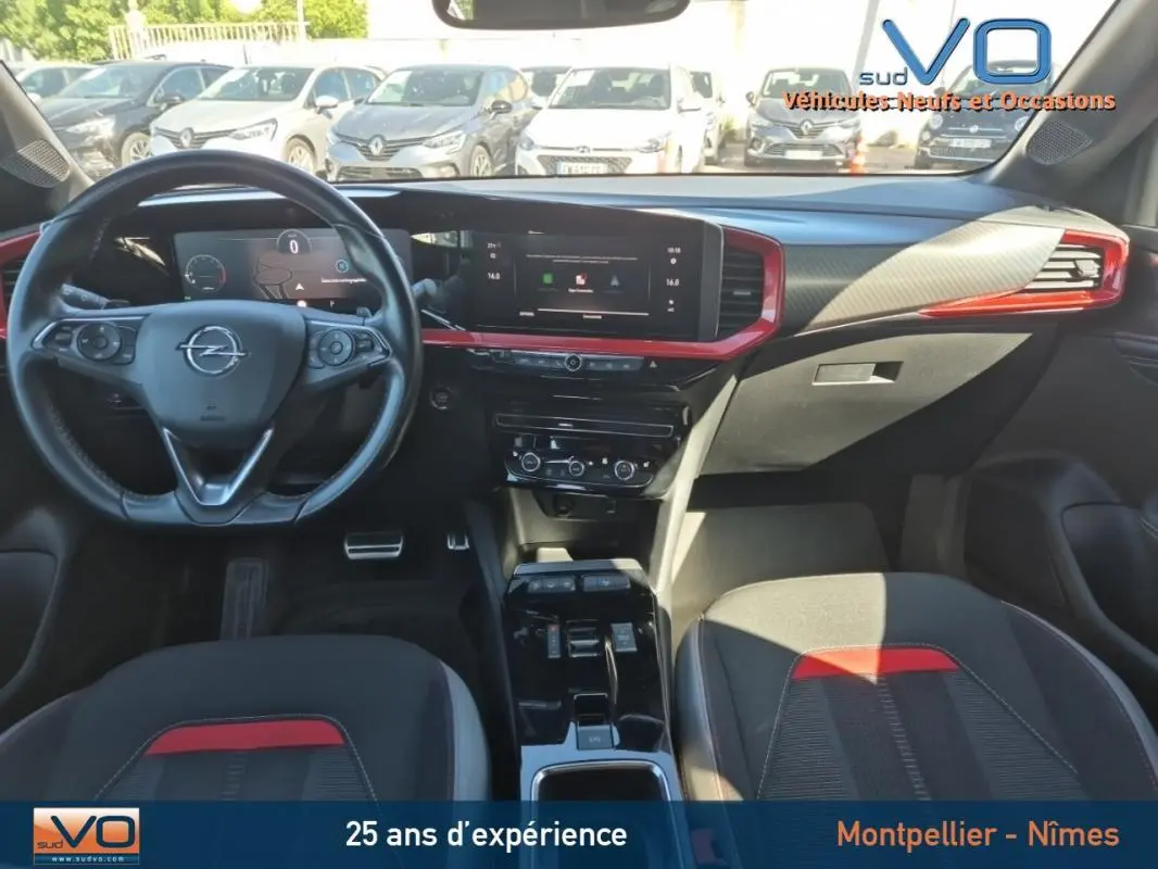 Intérieur avant de l'Opel Mokka 2022, tableau de bord noir avec inserts rouges et volant cuir multifonction.
