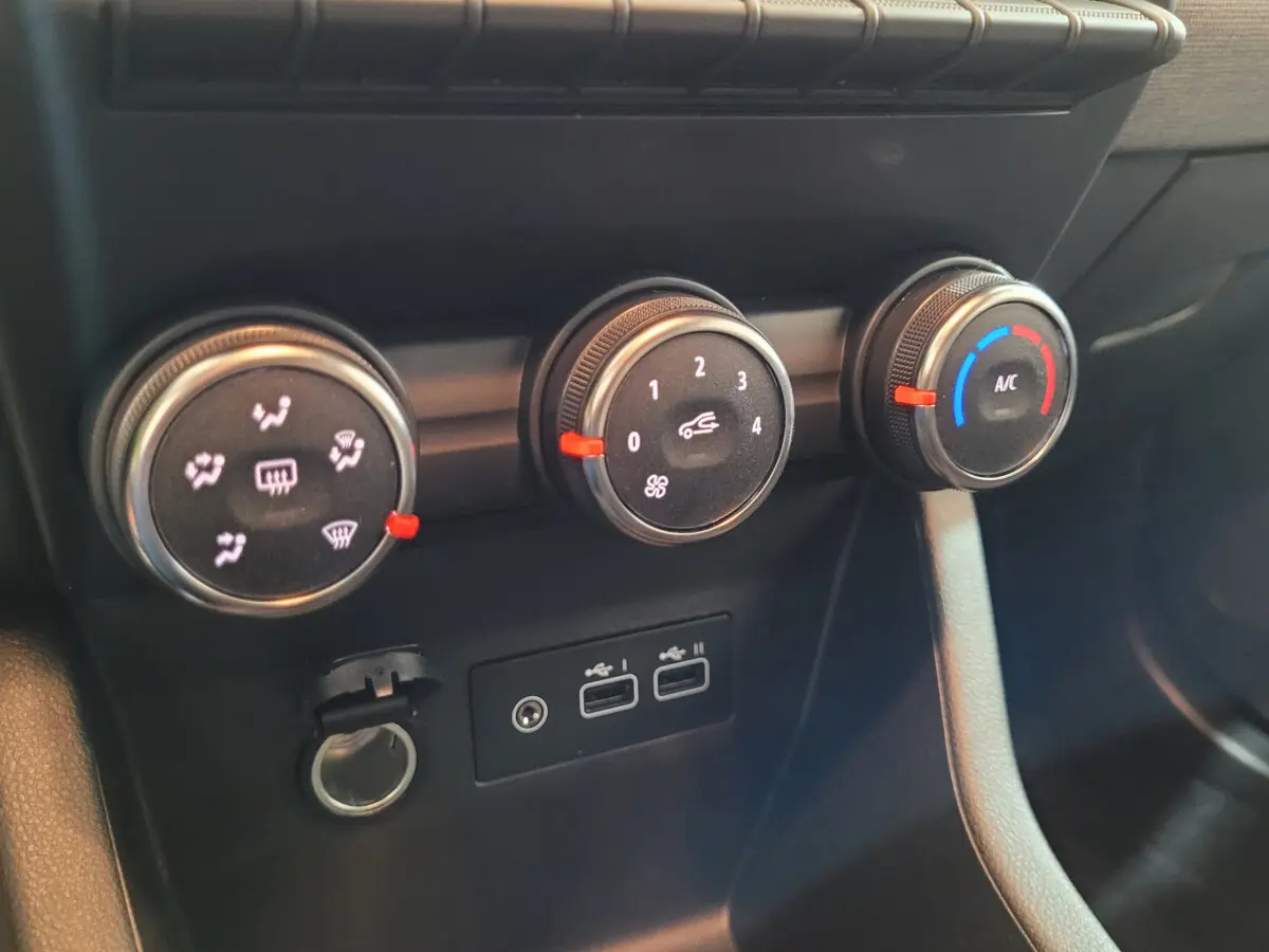 Gros plan sur les commandes de climatisation et les ports USB du tableau de bord de la Renault Clio gris foncé 2025.