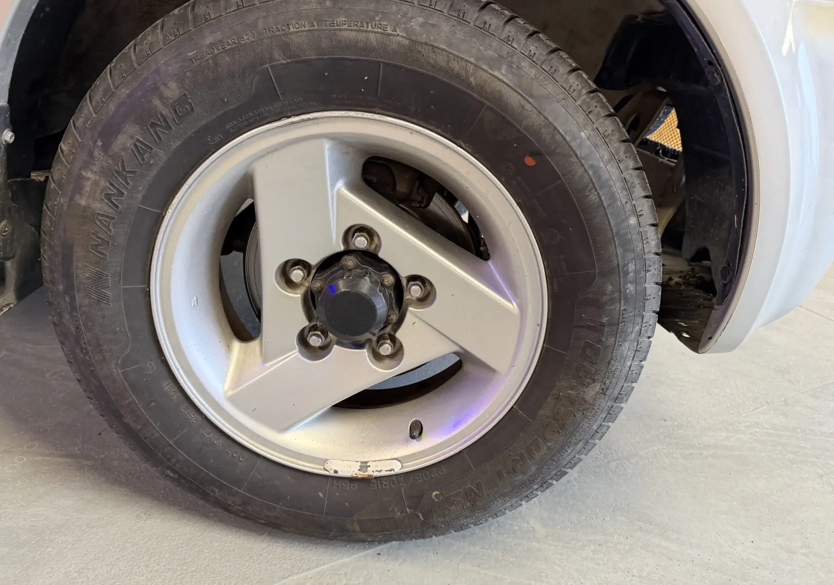 Gros plan sur la jante alu grise et le pneu Nankang du côté avant droit du Suzuki Jimny Cabriolet 2005.