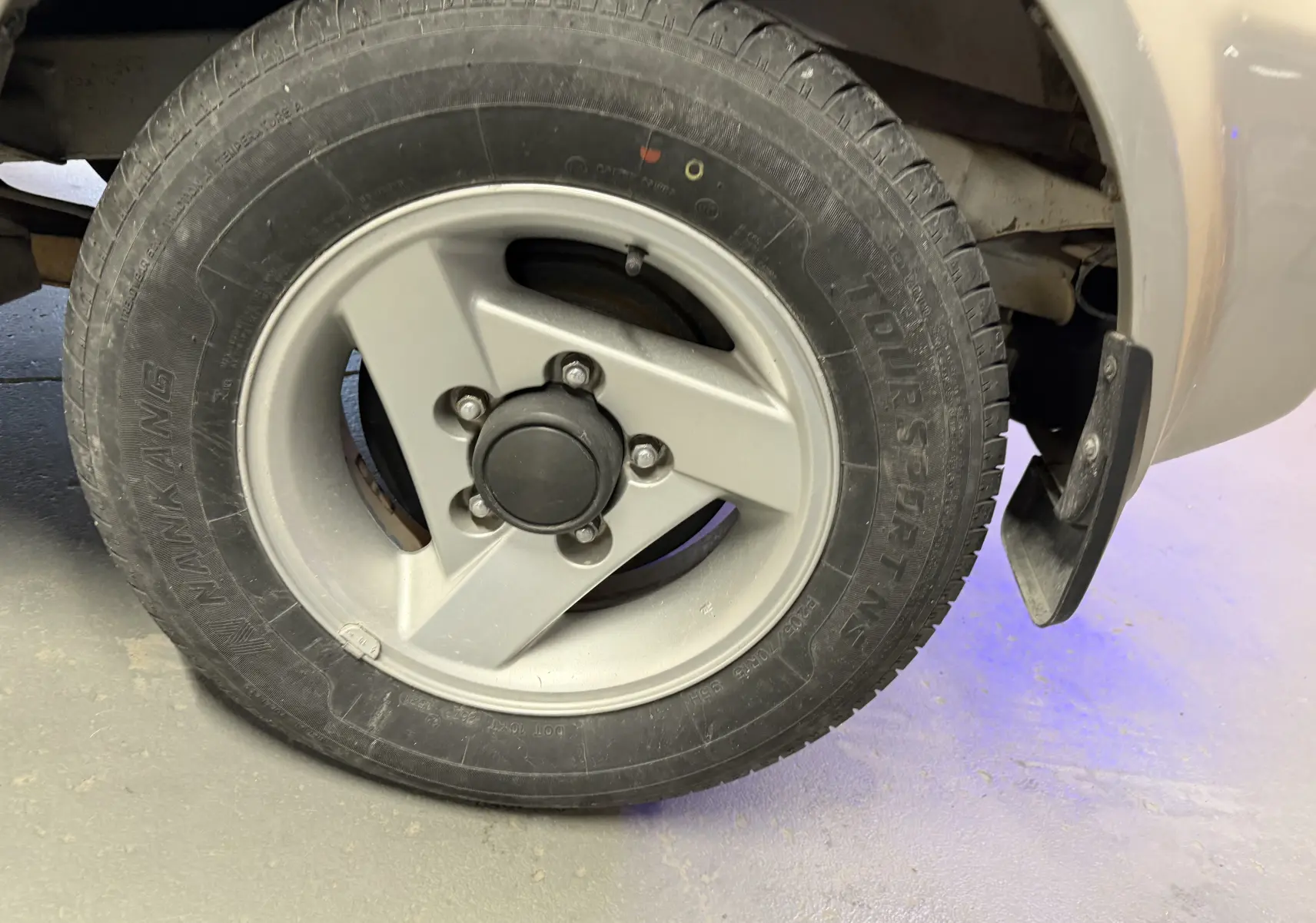 Gros plan sur la jante alu grise et le pneu Nankang du côté arrière droit du Suzuki Jimny Cabriolet 2005.