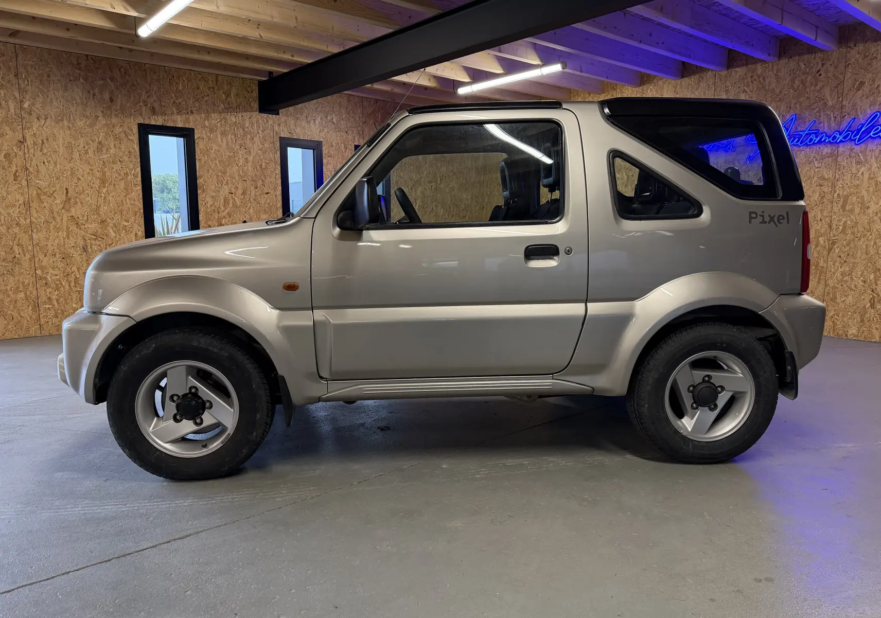 Vue de profil côté gauche du Suzuki Jimny Cabriolet gris 2005 avec hard-top et jantes alu en intérieur.