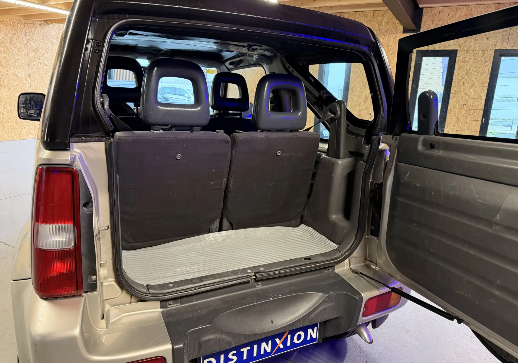 Vue arrière ouverte du Suzuki Jimny Cabriolet gris 2005, montrant l'intérieur et les sièges arrière rabattables.