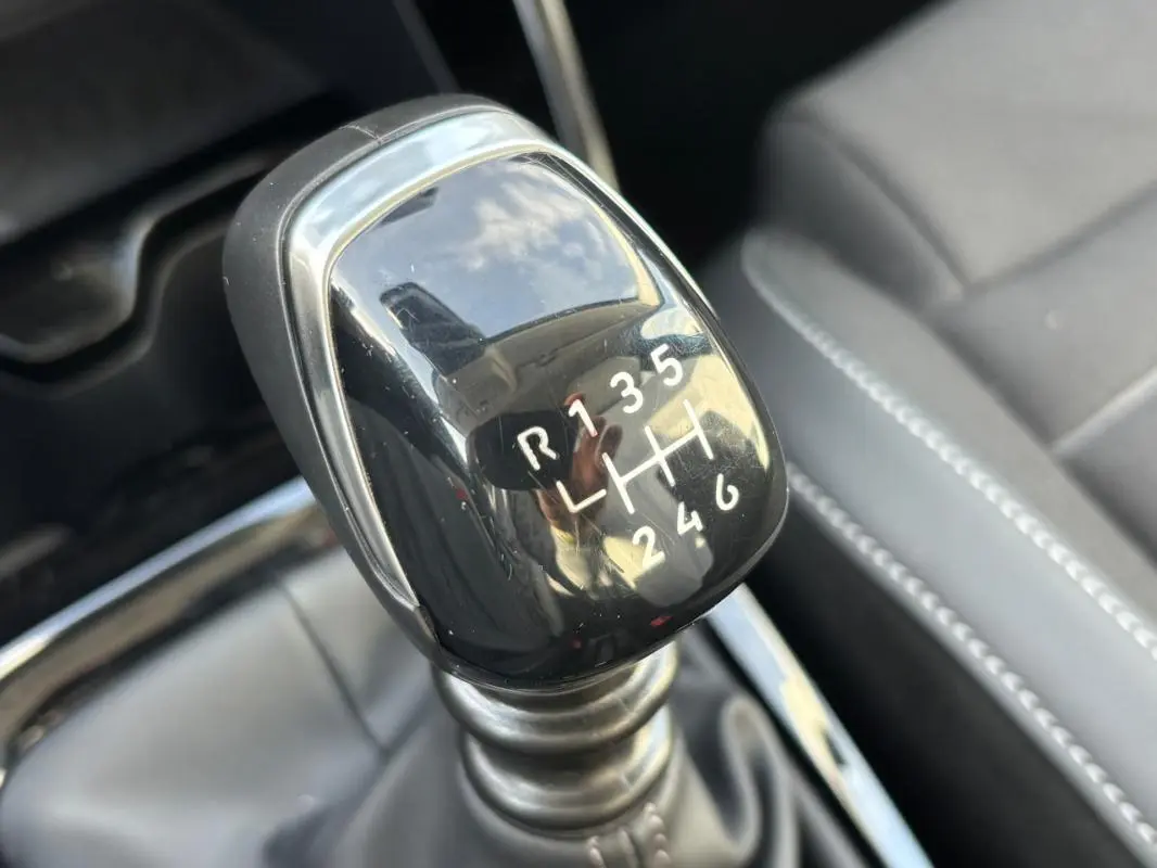 Gros plan sur le levier de vitesse manuel noir de la Citroën C3 Turbo 100 ch, avec coutures grises visibles sur les sièges.