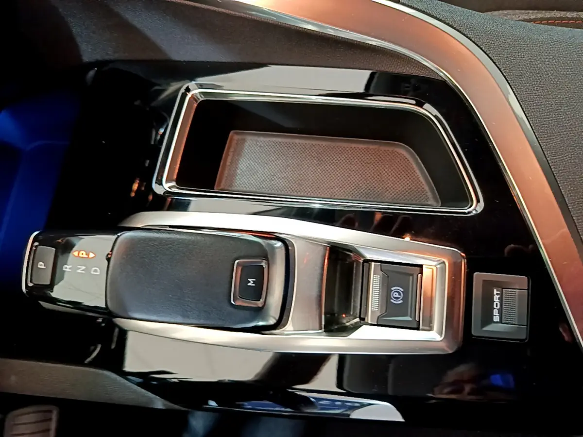 Gros plan sur la console centrale noire brillante du Peugeot 3008 2020 avec levier de vitesse automatique et bouton sport.