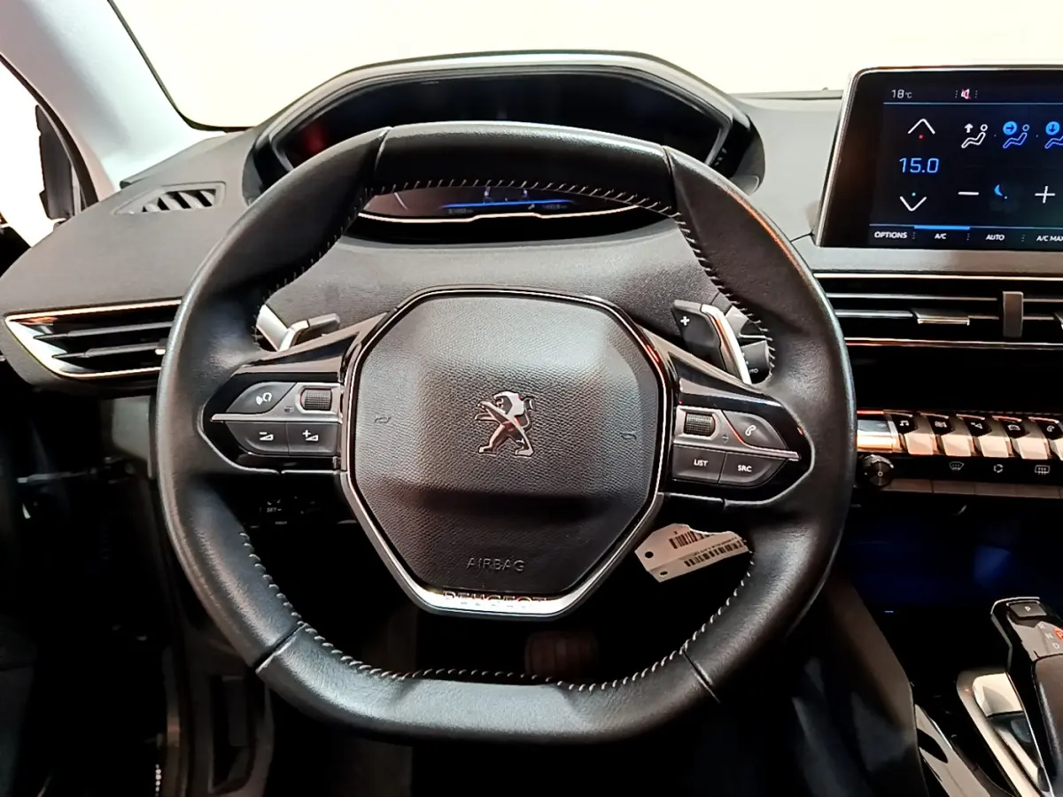 Vue rapprochée du volant cuir noir du Peugeot 3008 2020 avec tableau de bord numérique et écran tactile central.