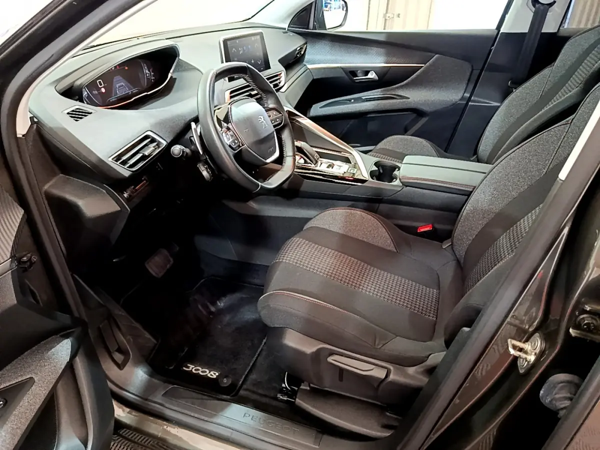 Intérieur avant droit du Peugeot 3008 gris foncé 2020, volant cuir, tableau de bord digital et sièges tissu gris.