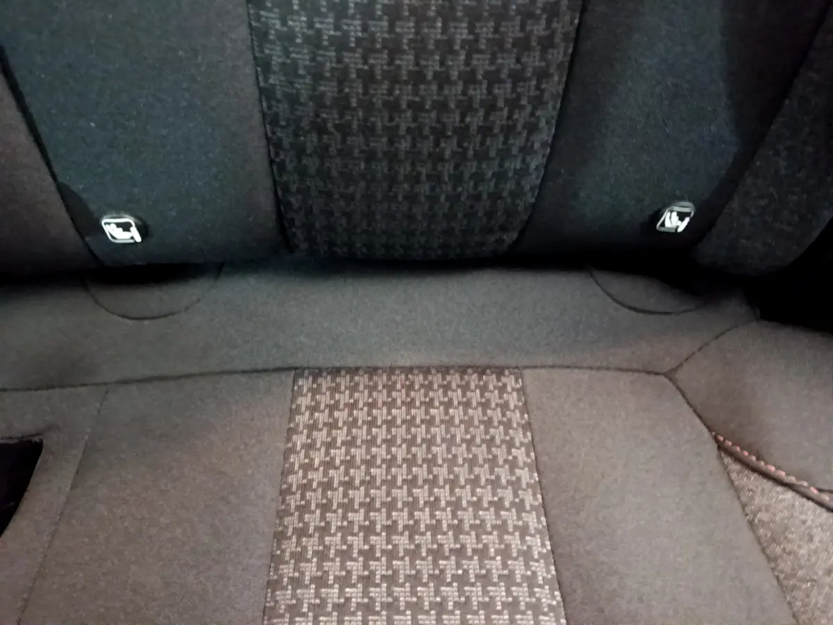Gros plan sur la banquette arrière en tissu gris foncé du Peugeot 3008, montrant les attaches Isofix intégrées.