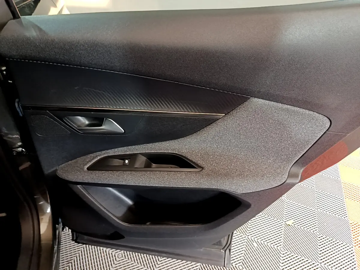 Détail de la porte côté gauche du Peugeot 3008 gris foncé, avec insert tissu et commandes des vitres intégrées.