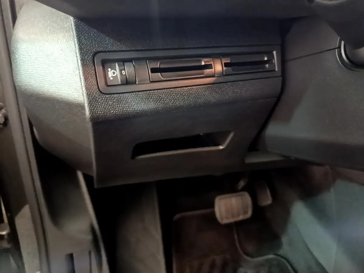 Détail du panneau de réglage des phares et des pédales côté gauche dans l'habitacle noir du Peugeot 3008 gris foncé