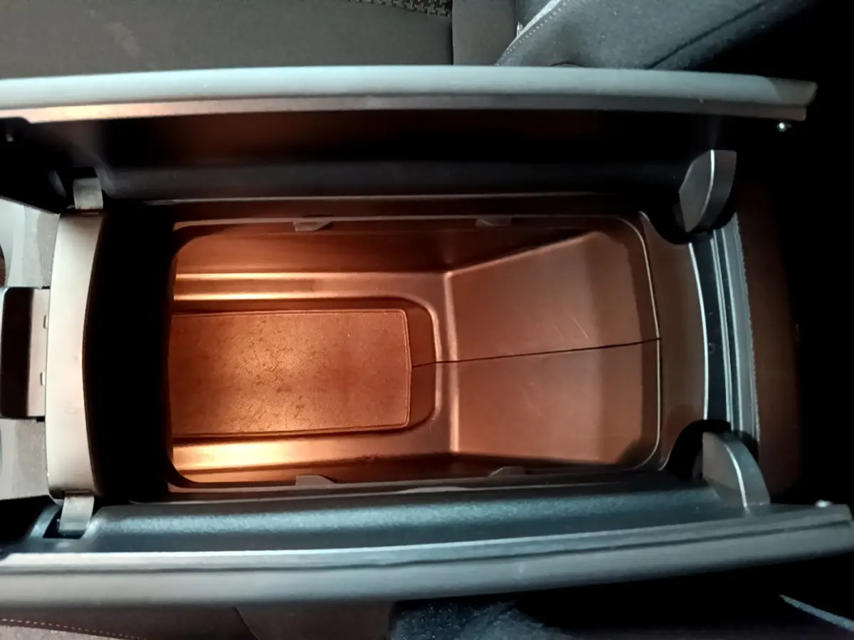 Vue en plongée sur le rangement central intérieur du Peugeot 3008 gris foncé, montrant un compartiment vide et éclairé.