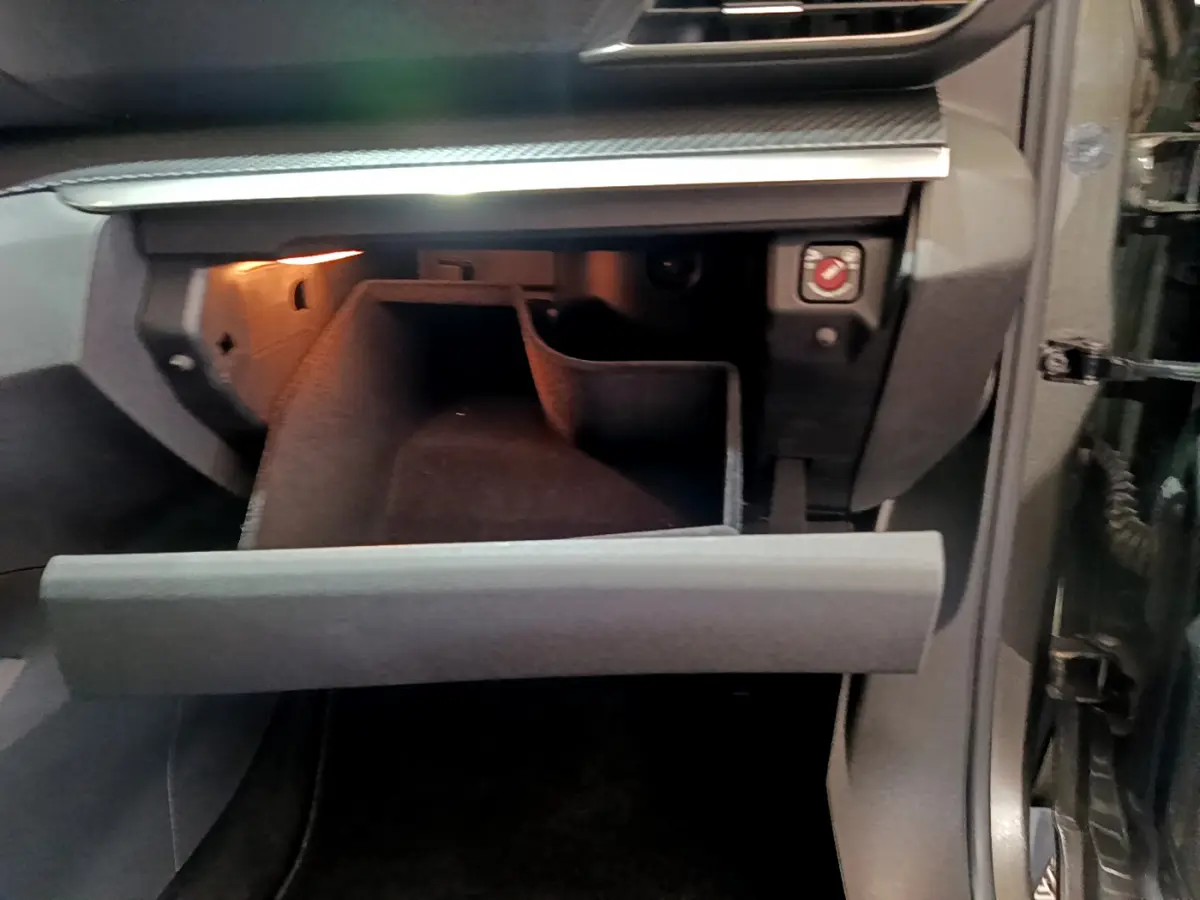 Gant de rangement ouvert côté passager intérieur d'un Peugeot 3008 gris foncé, éclairage intérieur visible