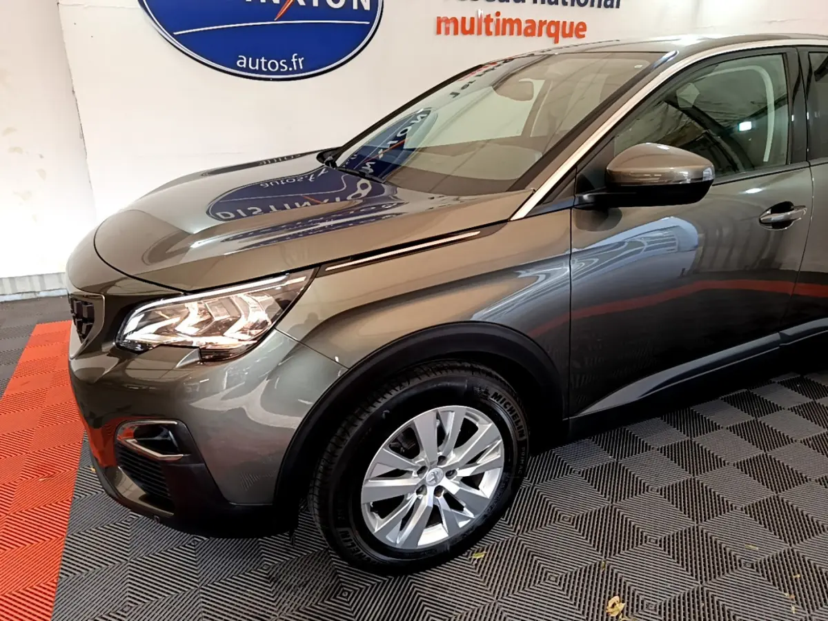 Vue 3/4 avant droit d'un Peugeot 3008 gris foncé avec phares LED allumés et jantes alliage visibles.