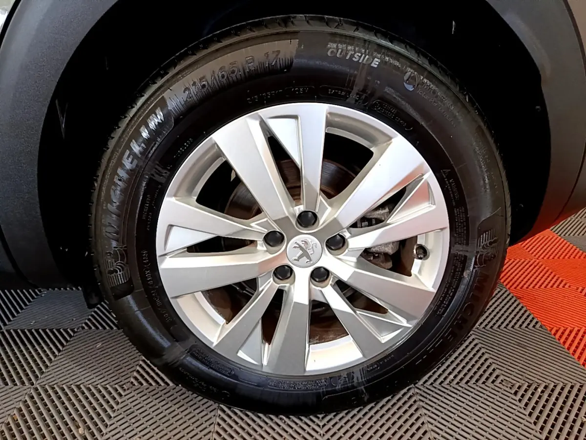 Gros plan sur la roue avant droite d’un Peugeot 3008 gris foncé, jante alliage à dix branches, pneu Michelin.