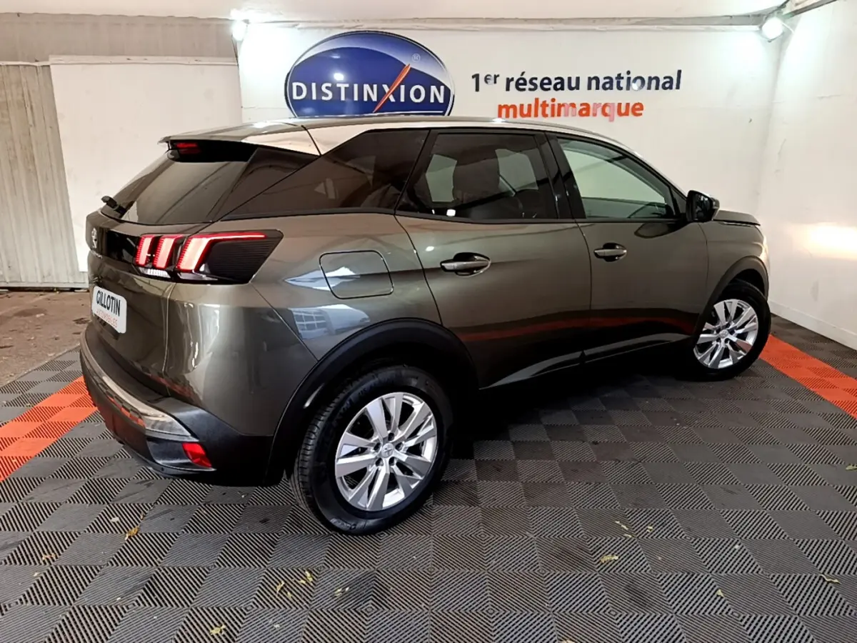 Vue 3/4 arrière droite d'un Peugeot 3008 gris foncé avec feux arrière LED et vitres teintées en intérieur showroom.