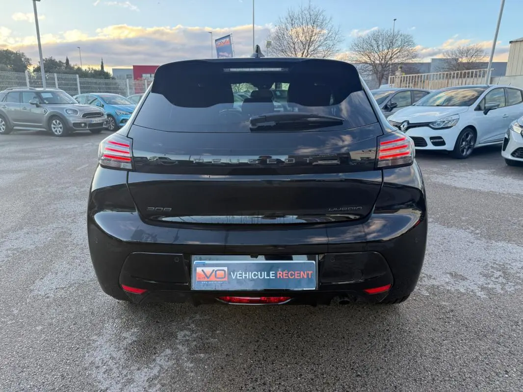 Vue arrière d'une Peugeot 208 Hybrid 110 noire de 2024, avec feux LED distinctifs et jantes alliage visibles.