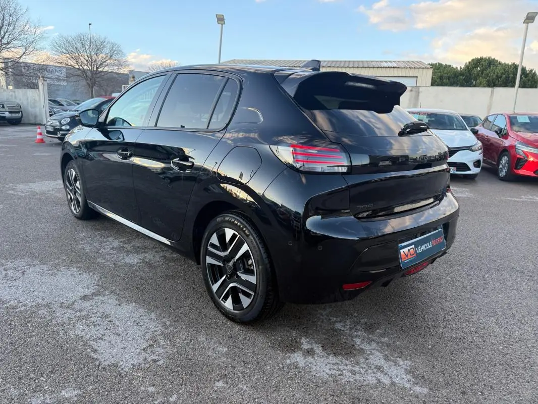 Vue 3/4 arrière droite d'une Peugeot 208 Hybrid 110 noire avec jantes alliage 16 pouces et antenne requin.
