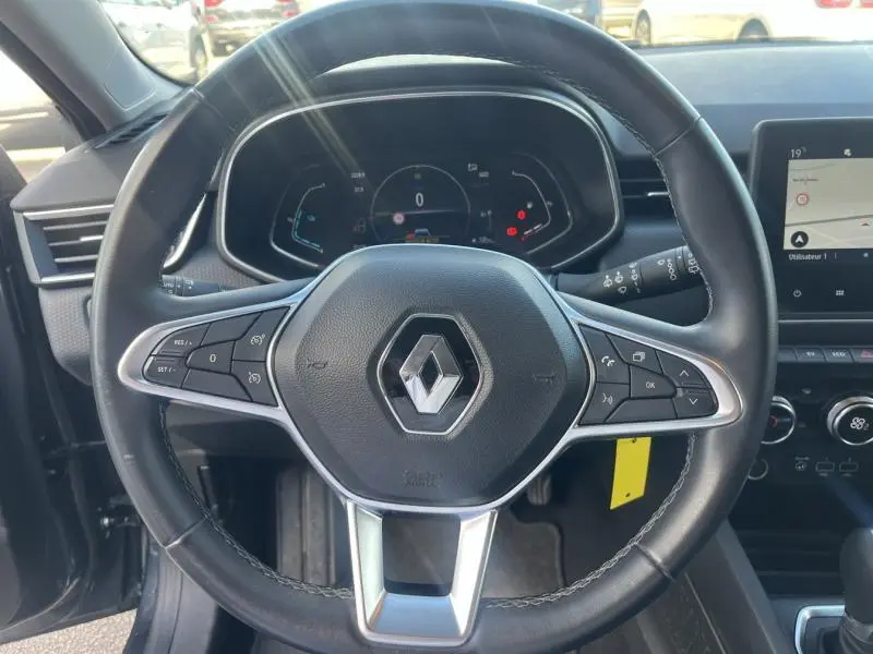 Vue rapprochée du volant multifonction noir de la Renault Clio 1.6 E-Tech 140ch Business 2021 avec tableau de bord numérique et écran tactile.