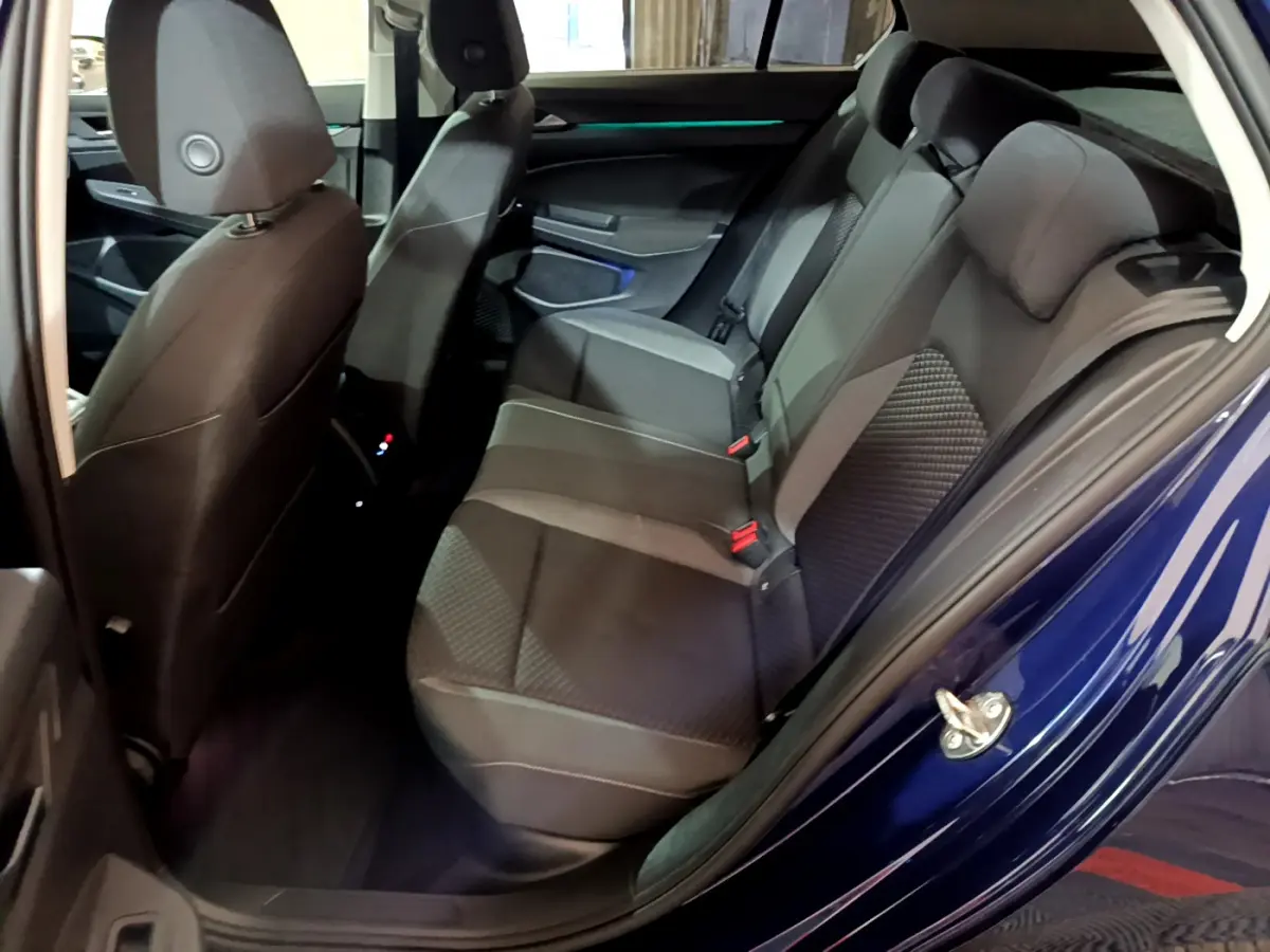 Vue côté gauche arrière de l'habitacle d'une Volkswagen Golf bleue 2022, sièges arrière en tissu gris foncé.