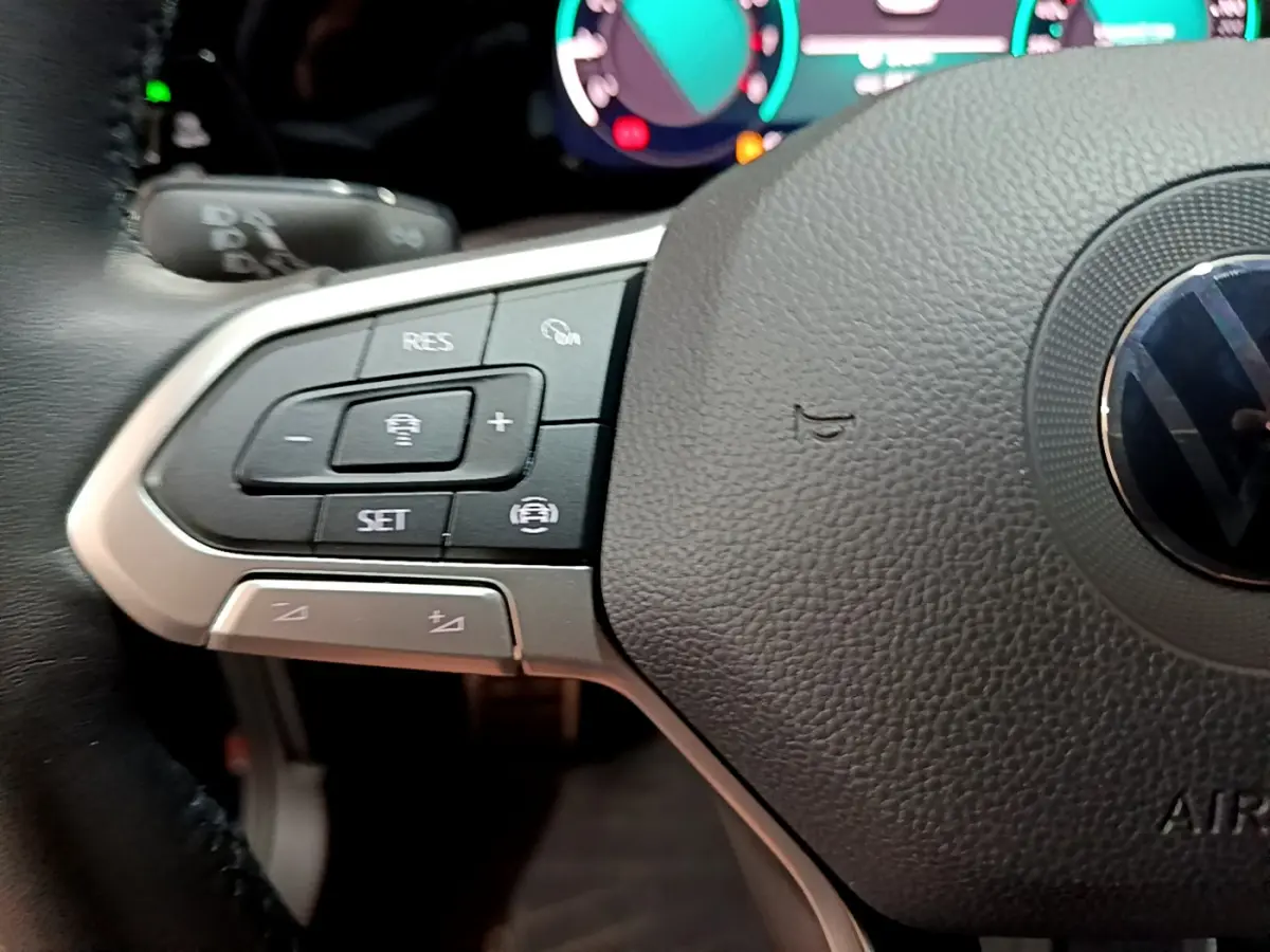 Gros plan sur le côté gauche du volant cuir noir de la Volkswagen Golf 1.0 TSI 2022 avec commandes multifonctions.