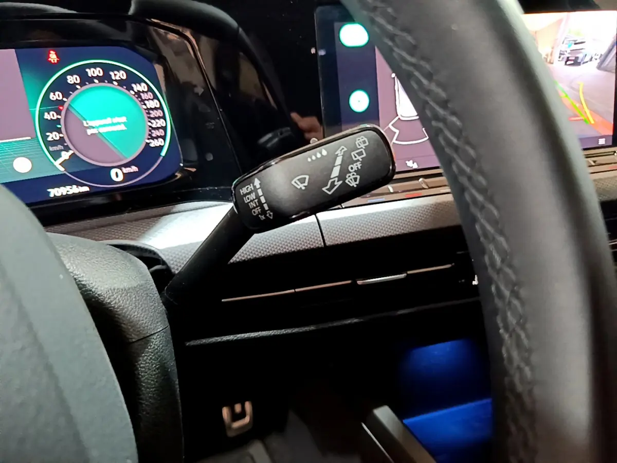 Gros plan sur le commodo d'essuie-glace et tableau de bord numérique d'une Volkswagen Golf bleue de 2022.