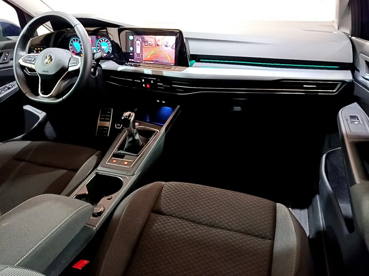 Vue intérieure avant droite de la Volkswagen Golf 1.0 TSI 2022 avec tableau de bord numérique et éclairage d'ambiance bleu