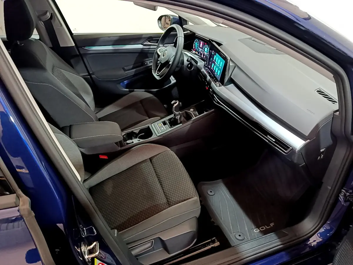 Intérieur côté conducteur d'une Volkswagen Golf bleu 2022, avec tableau de bord numérique et boîte manuelle visible.