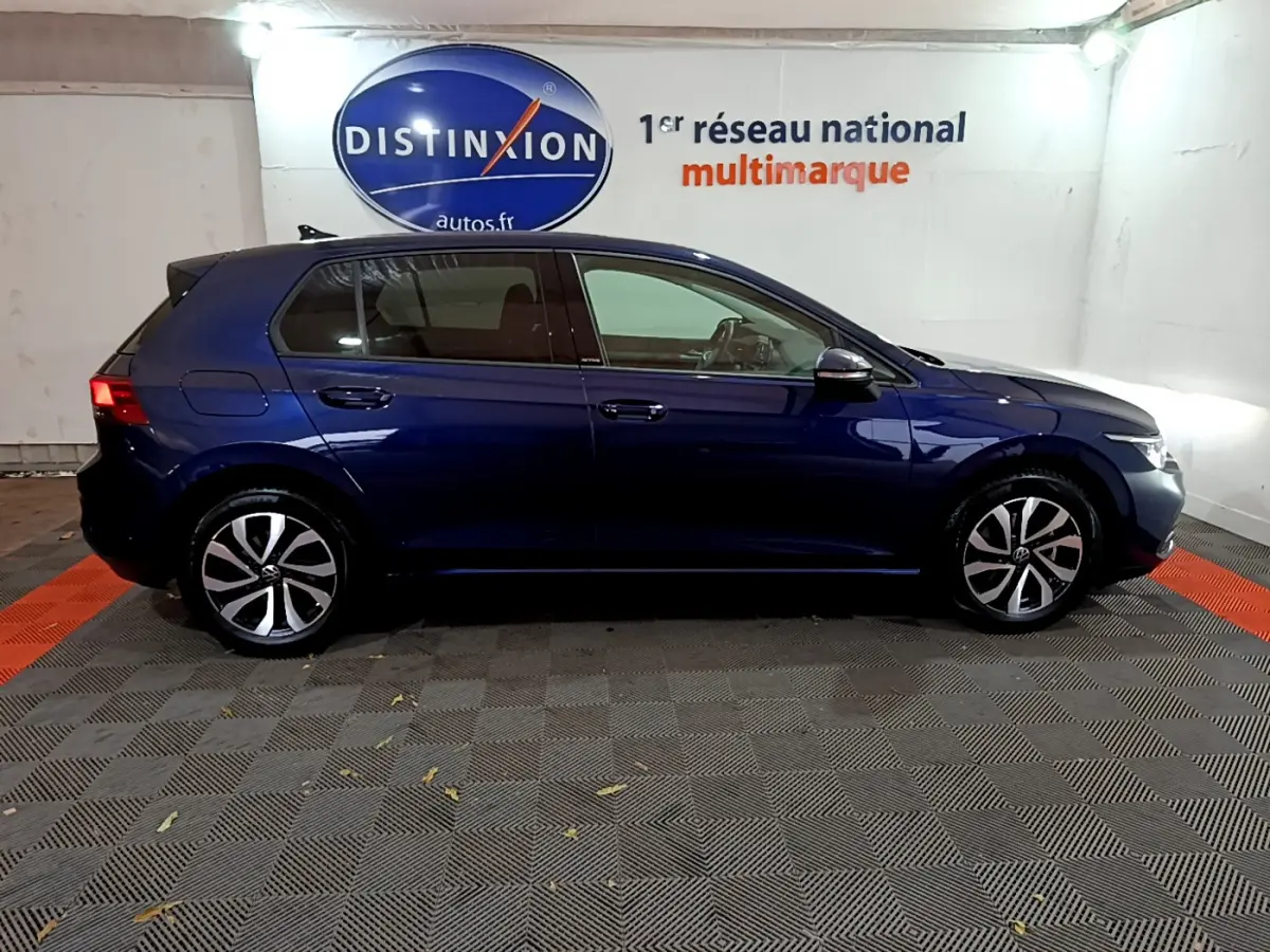 Profil droit d'une Volkswagen Golf bleu foncé 2022 garée en intérieur avec jantes alliage distinctives.
