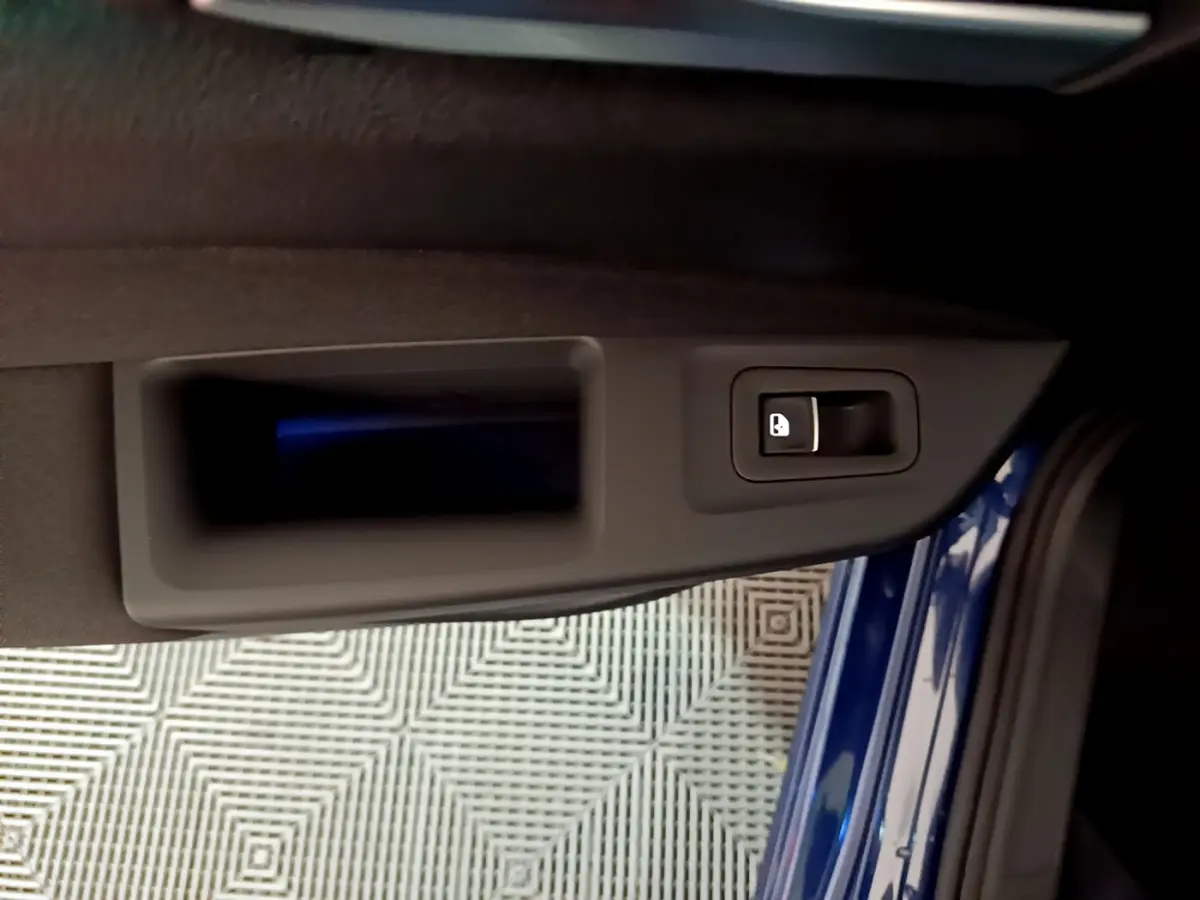 Poignée intérieure de porte côté gauche d'une Volkswagen Golf 2022 bleu, avec bouton de verrouillage intégré.