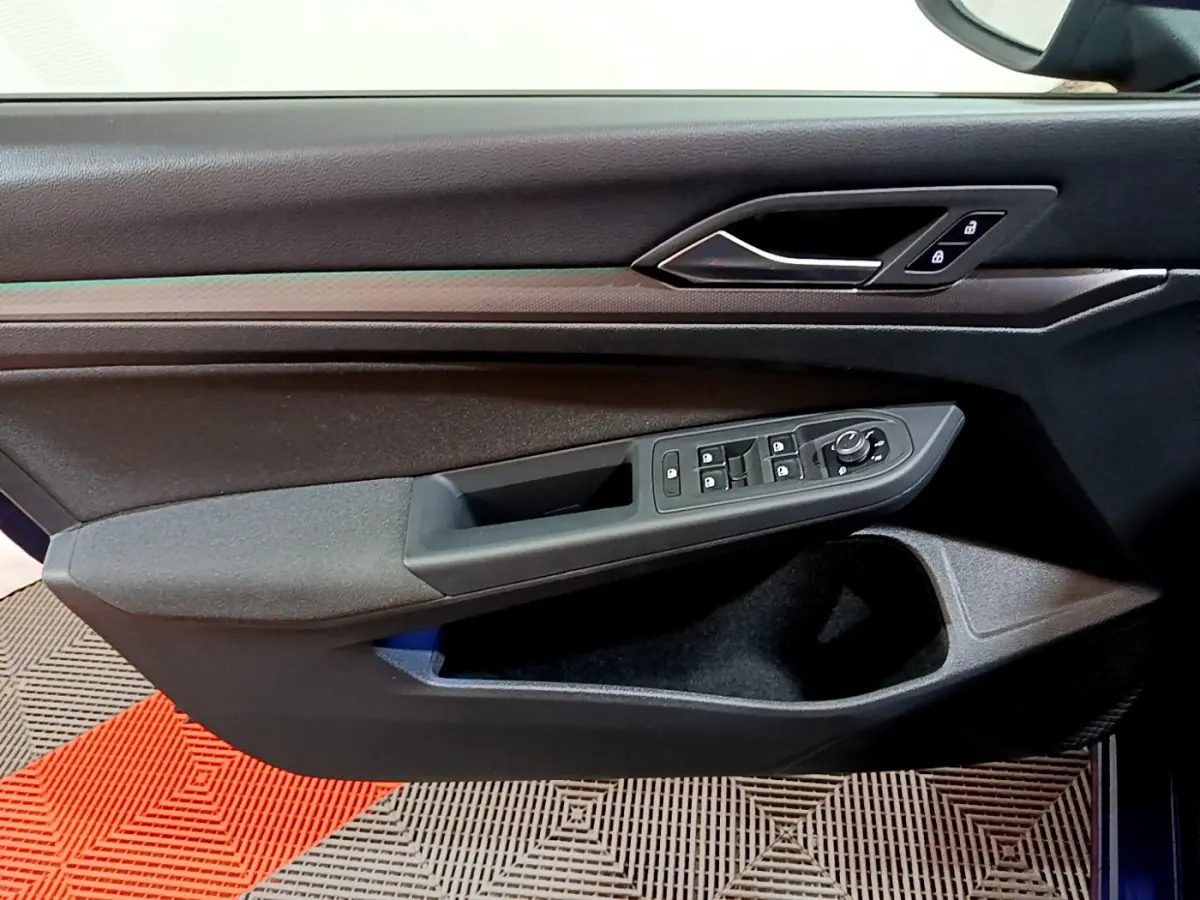 Vue rapprochée de la porte avant gauche noire de la Volkswagen Golf 1.0 TSI 2022 avec commandes de vitres et verrouillage.