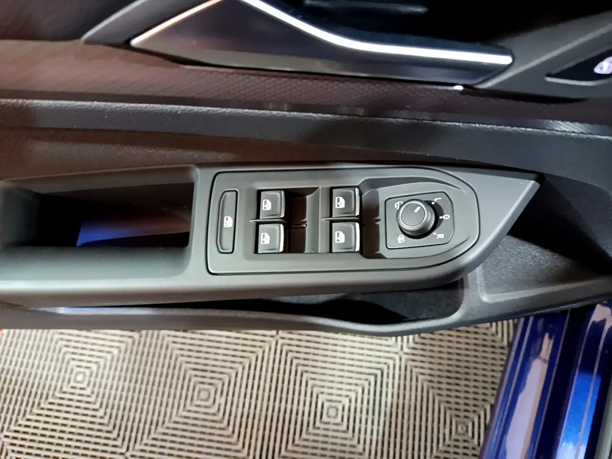 Gros plan sur la commande des vitres et rétroviseurs côté conducteur d'une Volkswagen Golf bleu 2022.