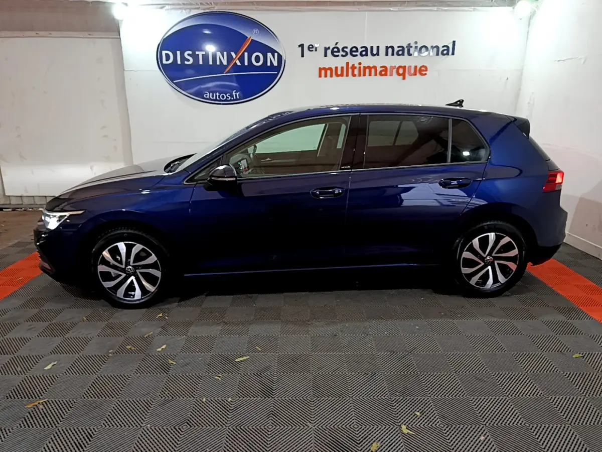 Profil côté gauche d'une Volkswagen Golf 1.0 TSI bleu foncé, avec jantes alliage et feux arrière allumés.