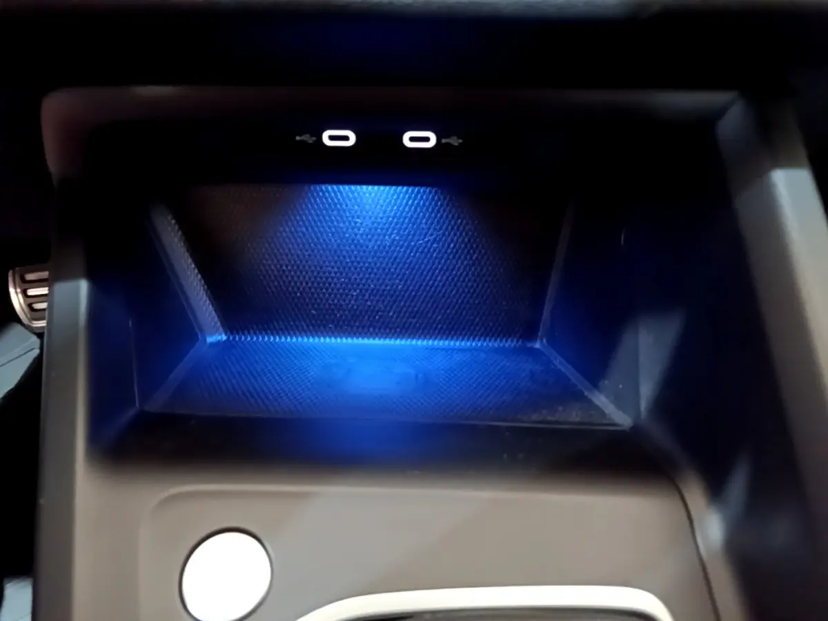 Gros plan sur la zone de recharge à induction bleutée avec deux ports USB-C dans une Volkswagen Golf 2022.