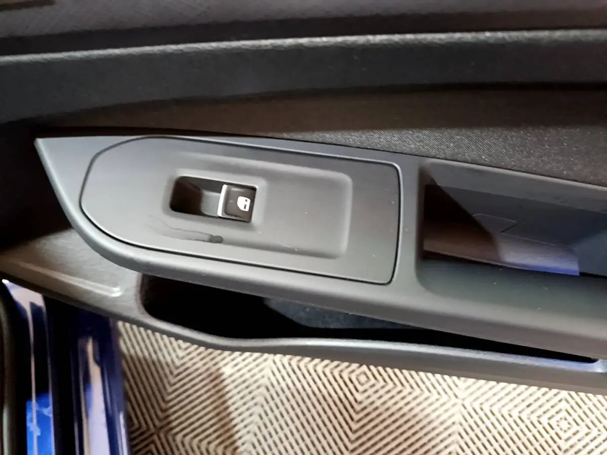 Gros plan sur la commande de verrouillage des portes côté gauche d'une Volkswagen Golf bleue 2022.