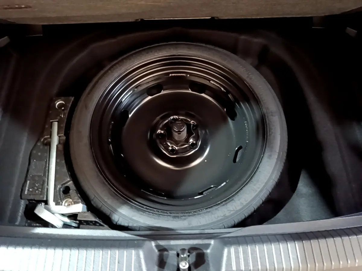 Roue de secours noire et outil de changement dans le coffre d'une Volkswagen Golf 1.0 TSI 2022.