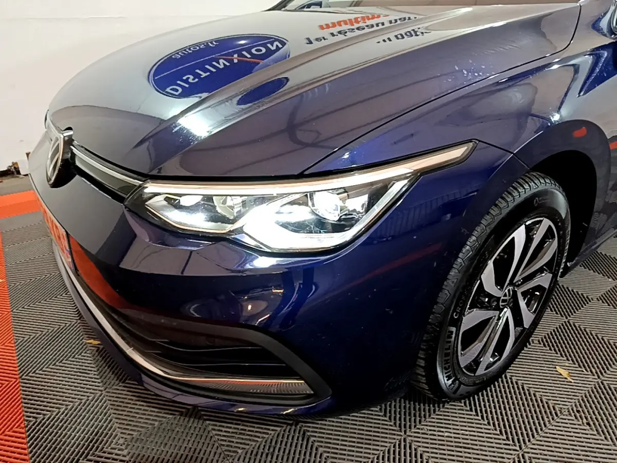 Vue 3/4 avant droit d'une Volkswagen Golf bleu métallisé avec phares LED et jantes alliage distinctives.