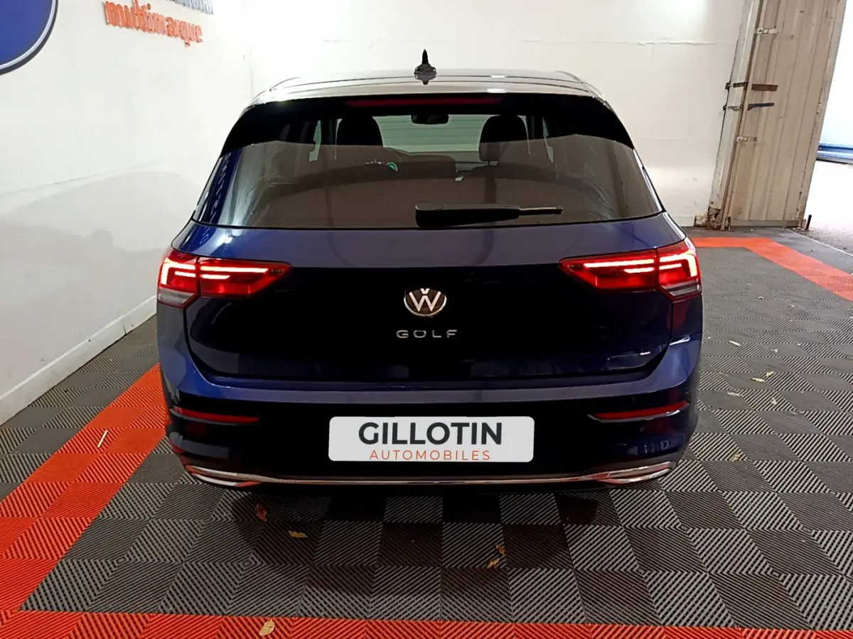 Vue arrière d'une Volkswagen Golf bleue 2022 avec feux LED allumés dans un garage intérieur.