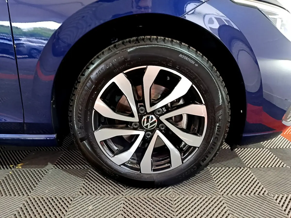 Gros plan sur la roue avant droite d'une Volkswagen Golf bleu 2022, avec jante alliage bicolore et pneu Michelin.