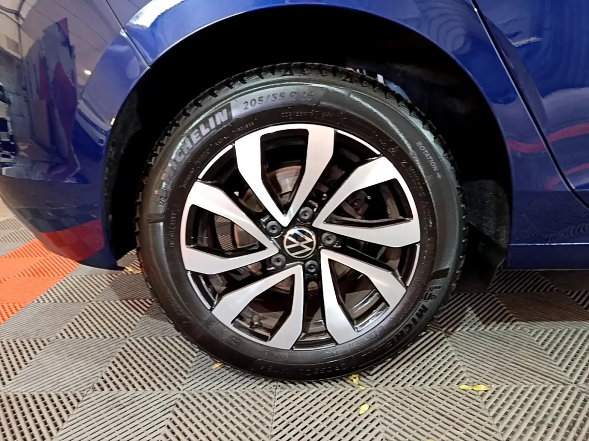 Gros plan sur la roue avant gauche d'une Volkswagen Golf bleu 2022 avec jante alliage bicolore et pneu Michelin.