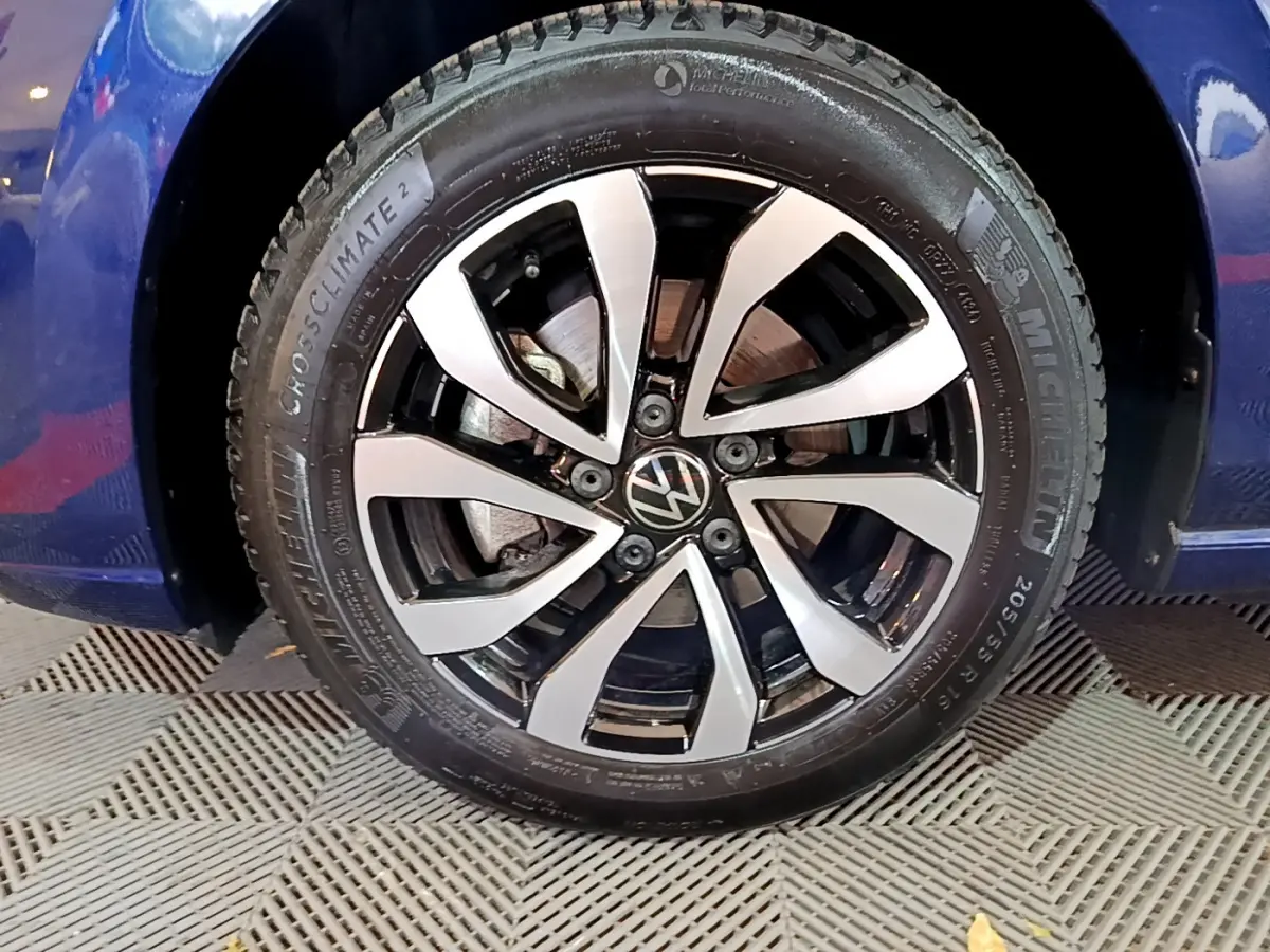 Gros plan sur la roue avant droite d'une Volkswagen Golf bleu 2022 avec jante alliage bicolore et pneu Michelin