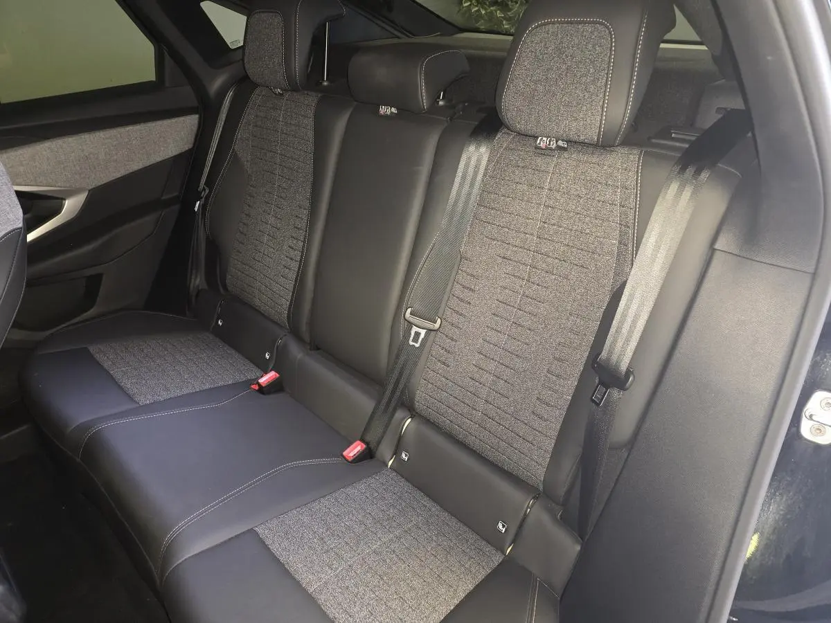 Vue intérieure côté droit sur la banquette arrière tissu gris et cuir noir du Peugeot 3008 noir hybride 2025.