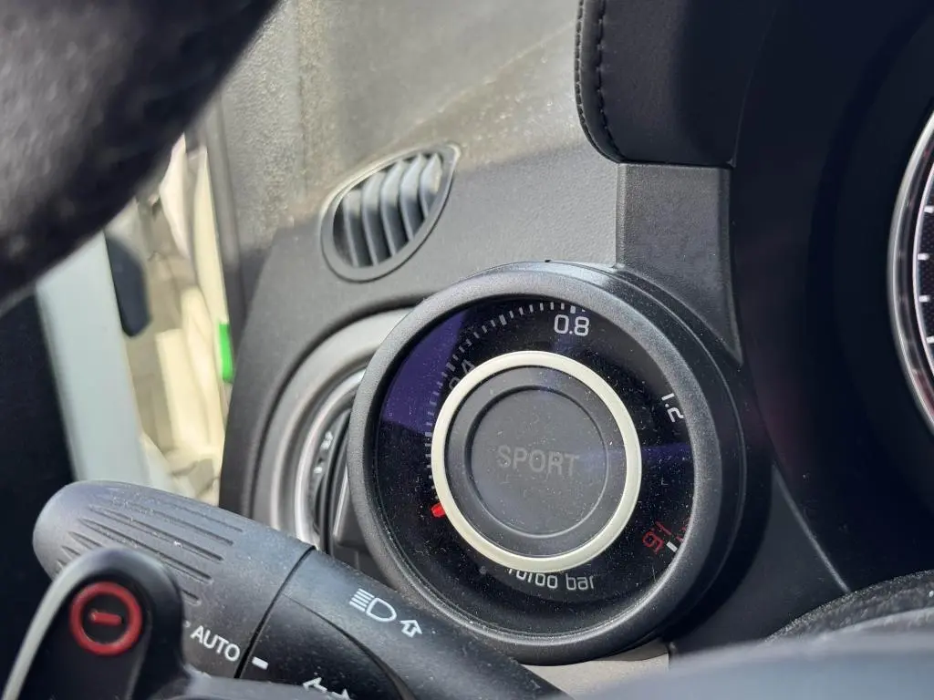 Gros plan sur le manomètre de pression turbo avec mode Sport dans l'habitacle de l'Abarth 500 blanc.