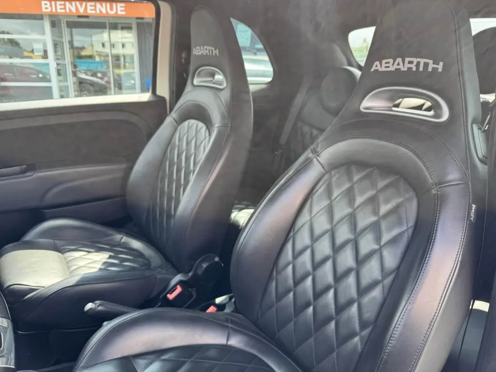 Gros plan sur les sièges sport en cuir noir avec logo ABARTH brodé, intérieur de l'Abarth 500 blanc 2021.