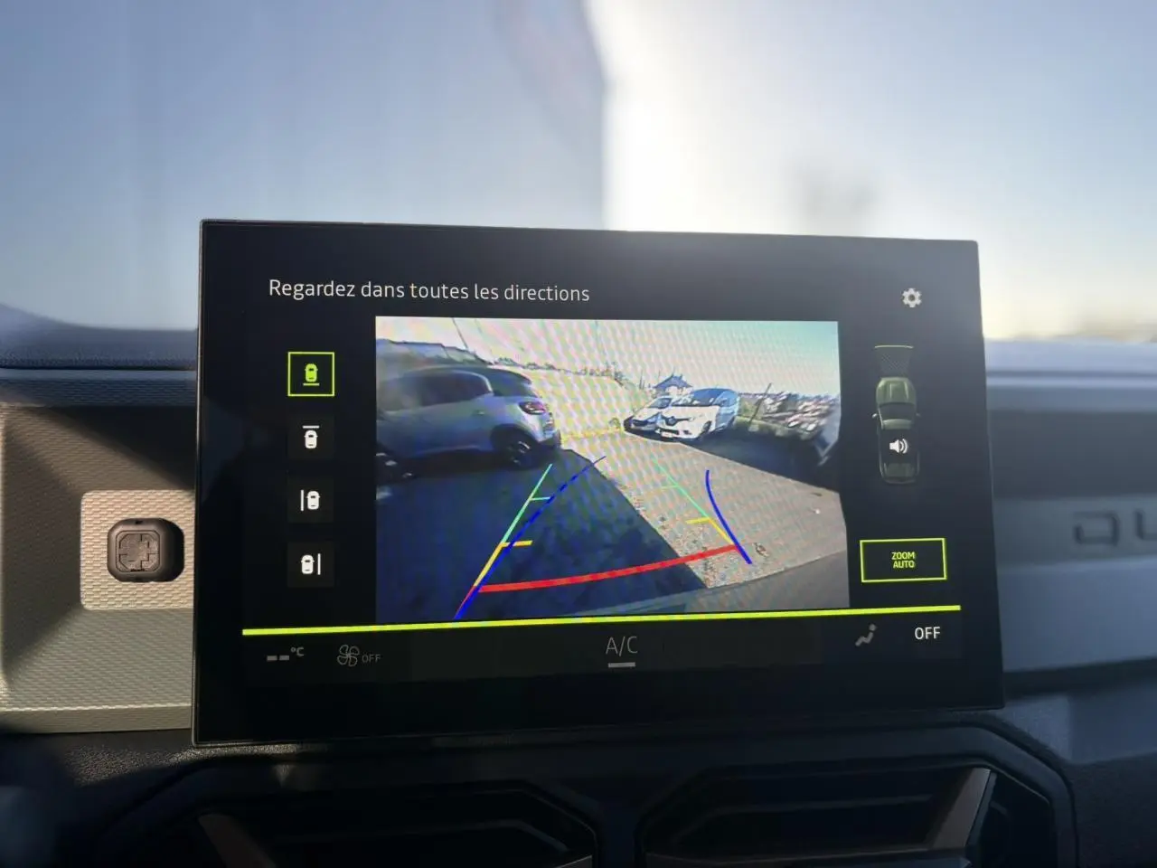 Écran tactile intérieur montrant la caméra multivues du Dacia Duster gris schiste en marche arrière avec guidage coloré.