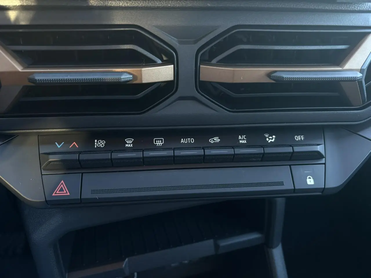 Détail de la console centrale du Dacia Duster 2026 gris, montrant les commandes de climatisation et les aérateurs noirs.