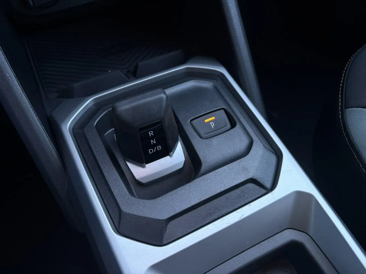 Gros plan sur la commande de boîte automatique et le bouton de parking du Dacia Duster gris Schiste, intérieur moderne.