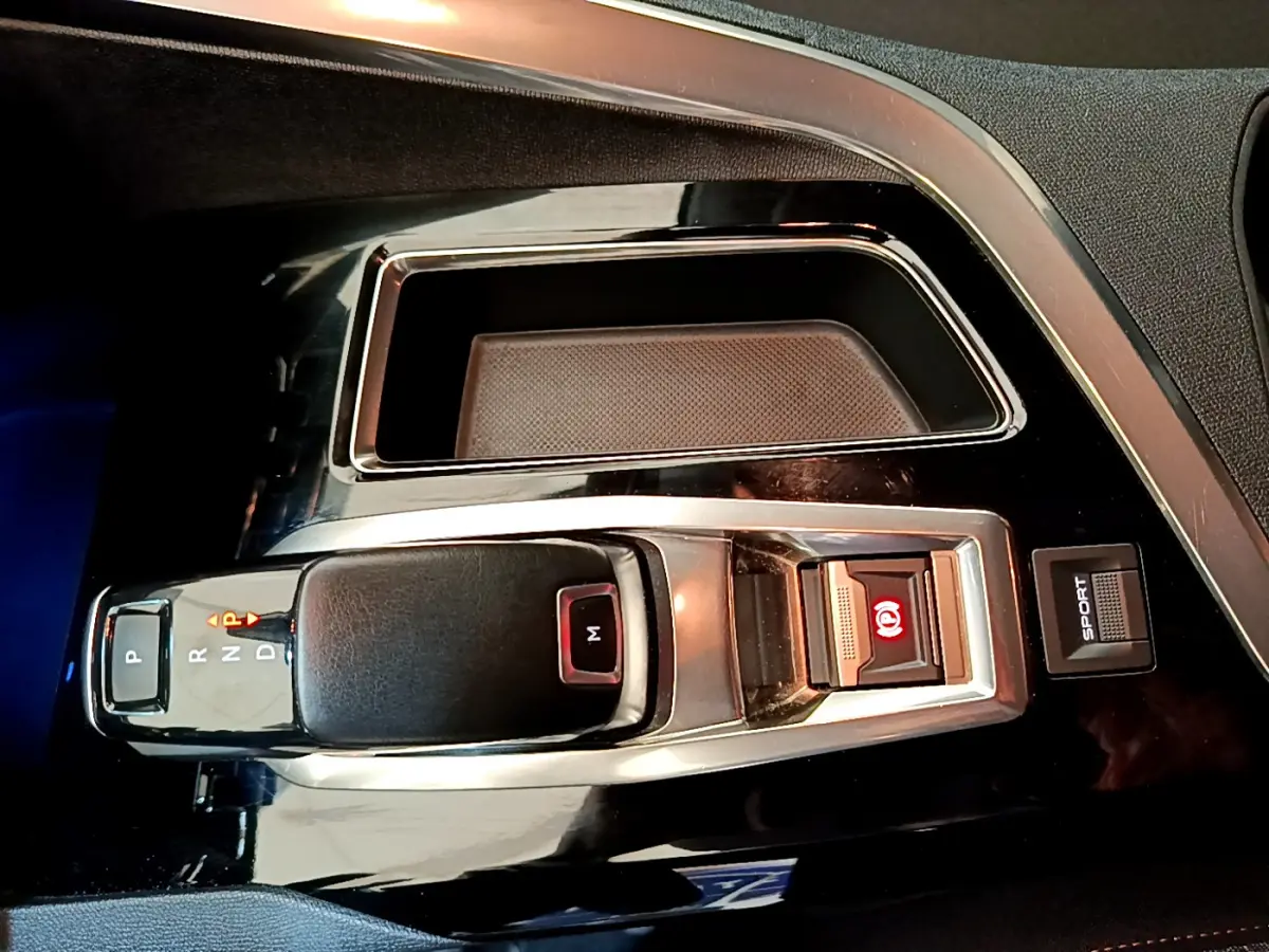 Gros plan sur la console centrale du Peugeot 3008 2020, avec levier de boîte auto noir et bouton mode Sport visible.