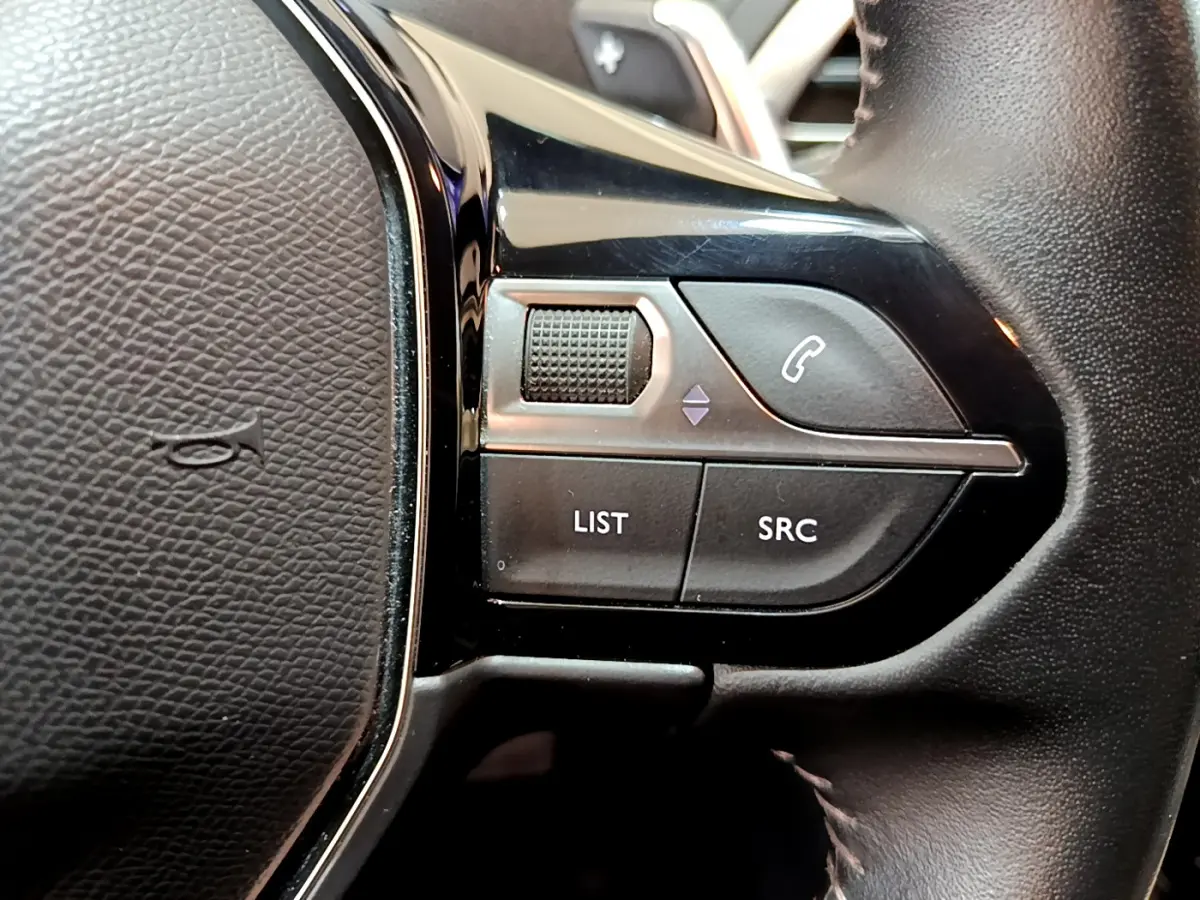 Gros plan sur les commandes gauche du volant cuir du Peugeot 3008 blanc, boutons LIST, SRC et téléphone.